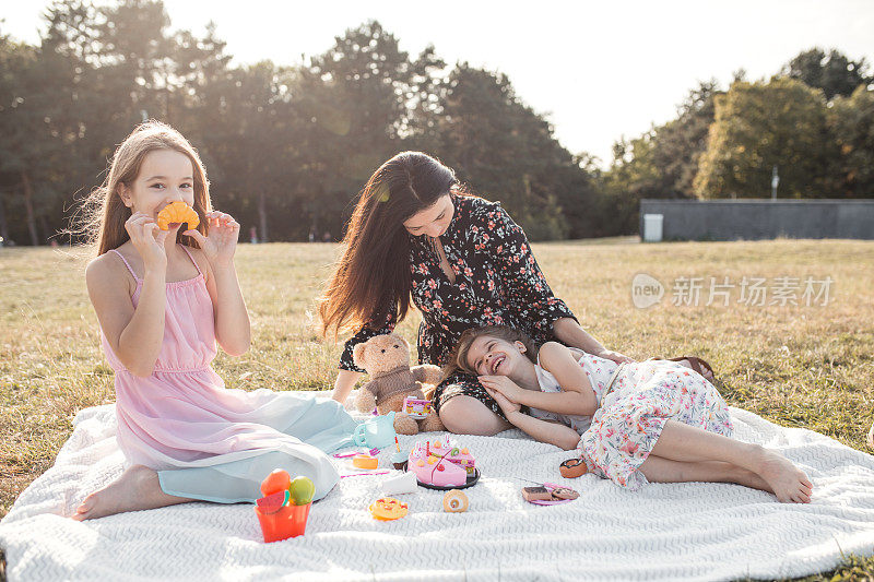 Mother two daughters and teddy bear having fun in park